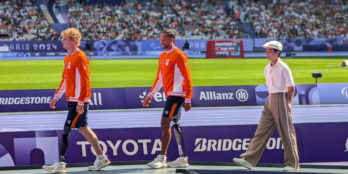 Walking out onto the podium stage at the Stade de France during the Paris 2024 Paralympic Games, behind two Dutch para-athletes, a full crowd in the stands behind