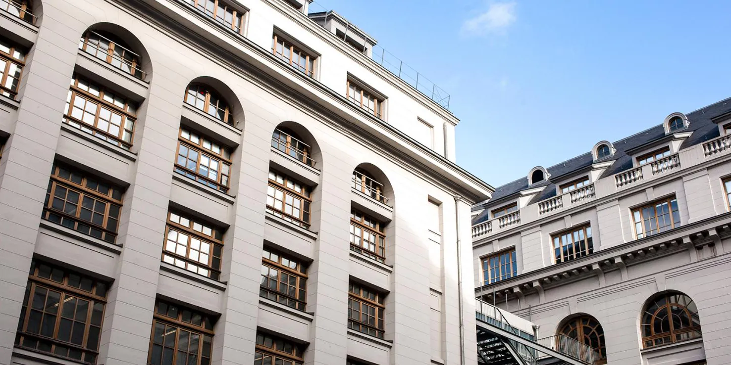 The courtyard of the Grands Moulins building at Universite Paris Cite, arched windows rising against a clear sky
